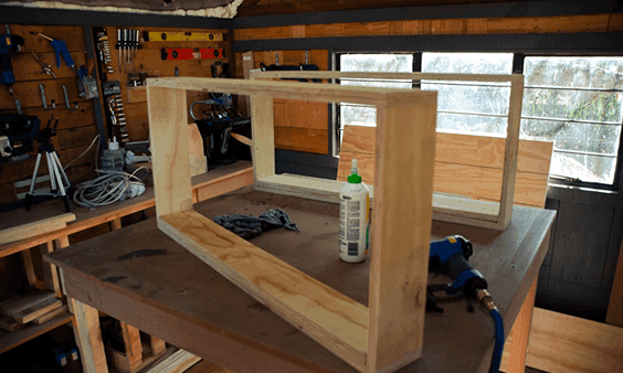 Wooden frame construction on a workbench, with wood glue and power tools.