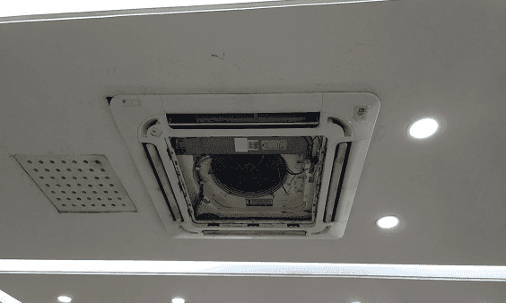 Ceiling-mounted air conditioning unit with its internal components exposed for maintenance or repair.